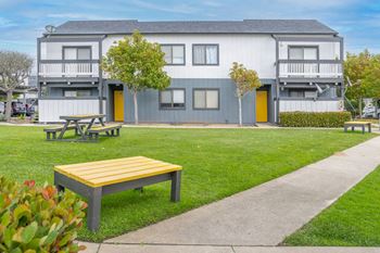a park with benches in front of an apartment building at The Gates at The Marina Apartments, Marina, CA